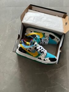 Multicolour low-top sneakers with black-and-white cow-print panels, turquoise toe sections, yellow accents, and a green outsole