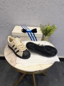 Beige black and silver shell-toe sneakers with metallic side stripes and black outsole
