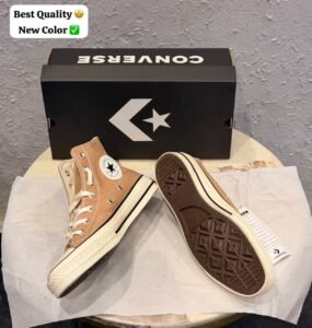 Beige high-top canvas-style sneakers with cream laces, metal eyelets, an off-white midsole with black pinstripes, and a dark brown patterned outsole