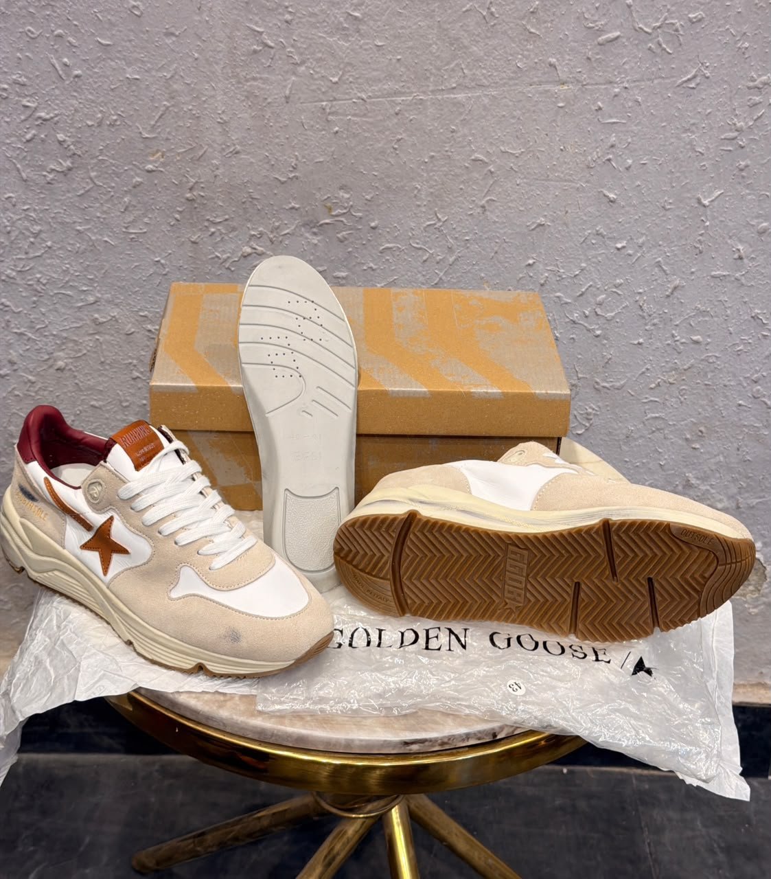 Beige and white low-top sneakers with brown star detailing, layered panels, and a chunky cream sole