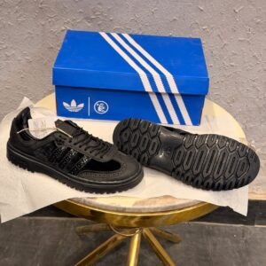 All-black brogue-style sneakers with perforated detailing, textured panels, and chunky platform soles