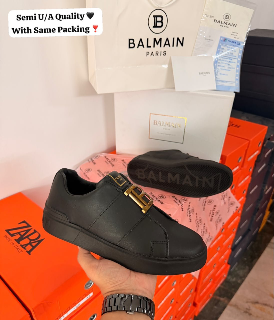 Black low-top sneakers with a gold-tone buckle detail and matching dark sole