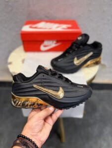 Black sneakers with sculpted side panels, metallic gold accents, and a decorative gold heel section