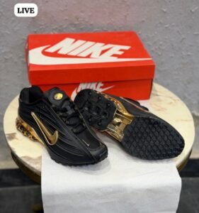 Black sneakers with sculpted side panels, metallic gold accents, and a decorative gold heel section