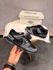 Black and charcoal grey low-top sneakers with layered panels, a perforated toe, grey outsole, and additional black laces.