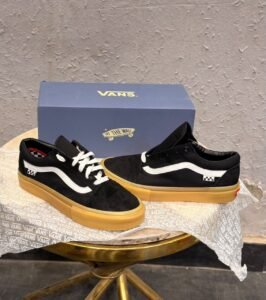 Black low-top sneakers with white side detailing, white laces, checkerboard-inspired heel accents, and a gum-coloured sole