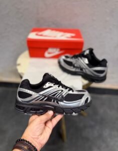 Black sneakers with metallic silver overlays, mesh-style panels, and a sculpted dark outsole