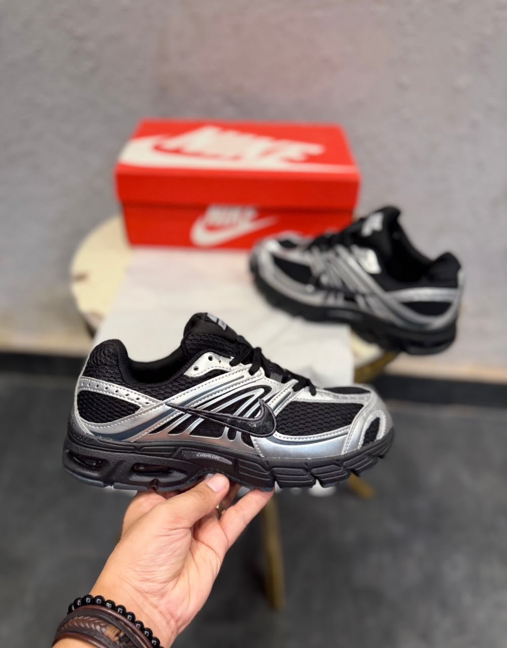 Black sneakers with metallic silver overlays, mesh-style panels, and a sculpted dark outsole