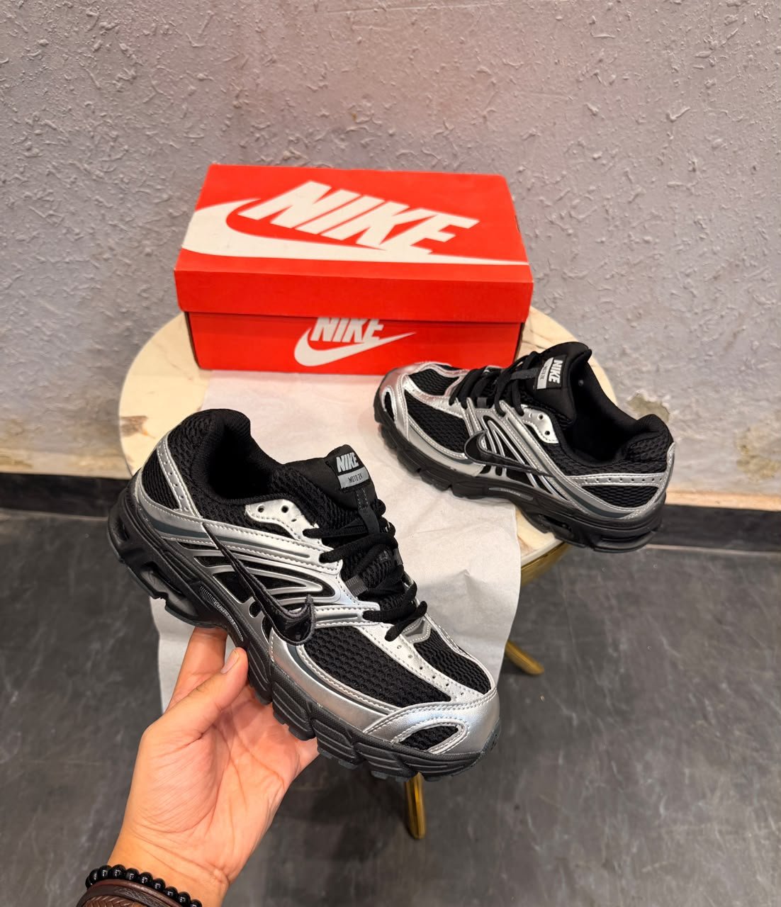 Black sneakers with metallic silver overlays, mesh-style panels, and a sculpted dark outsole