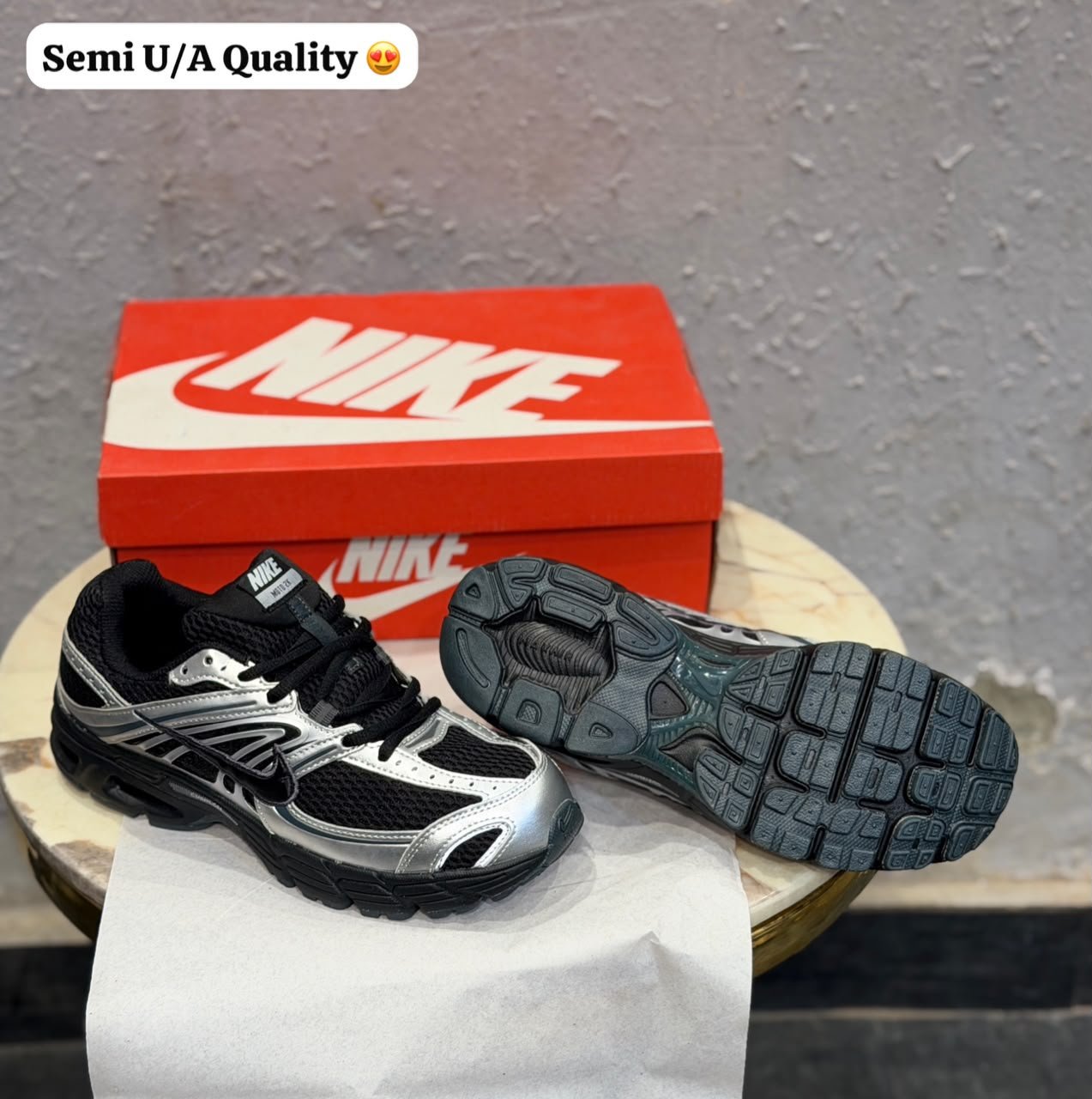 Black sneakers with metallic silver overlays, mesh-style panels, and a sculpted dark outsole