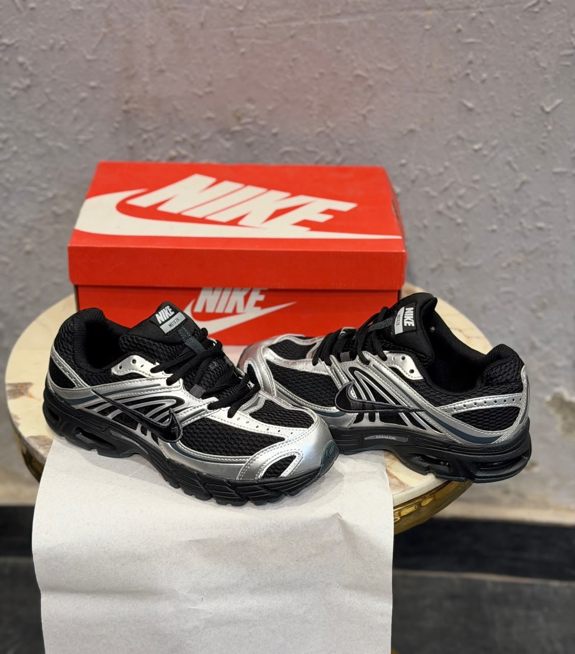 Black sneakers with metallic silver overlays, mesh-style panels, and a sculpted dark outsole
