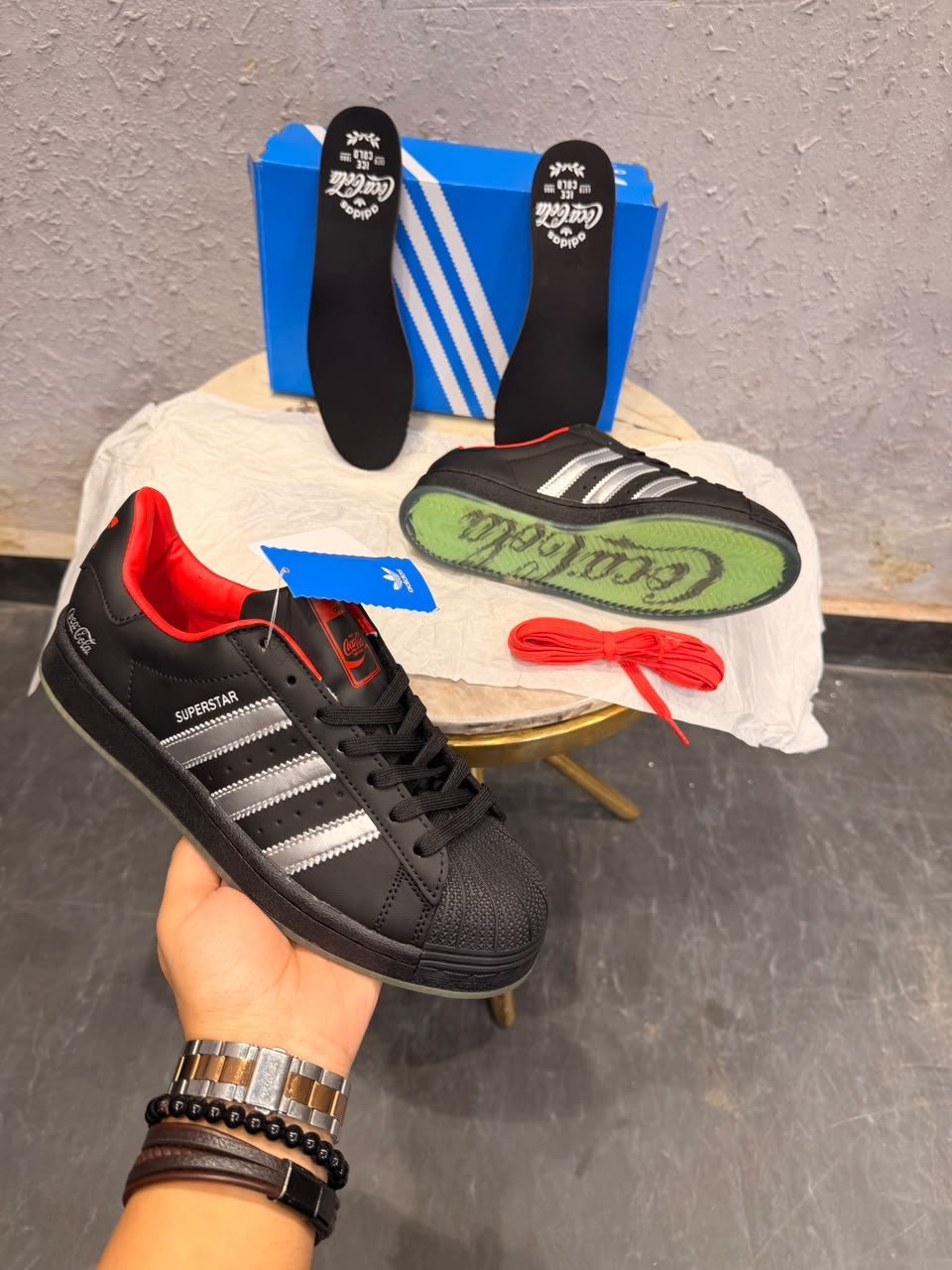 Black Retro Sneakers – Red Accent Shell-Toe Streetwear Edition (2) Black retro low-top sneakers with silver-toned stripes, red accents, a textured shell-shaped toe, and a green-toned outsole