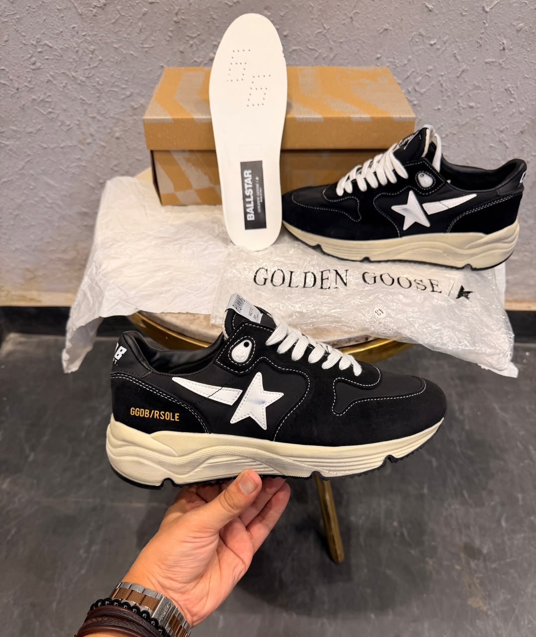 Black running-inspired sneakers with white star details, contrasting stitching, white laces, and a chunky cream sole