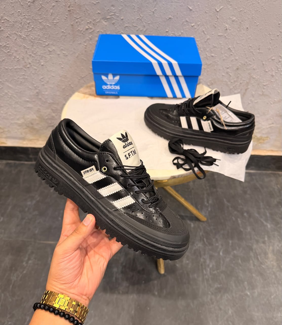Black and white retro sneakers with contrasting side stripes, perforated panels, and chunky black soles