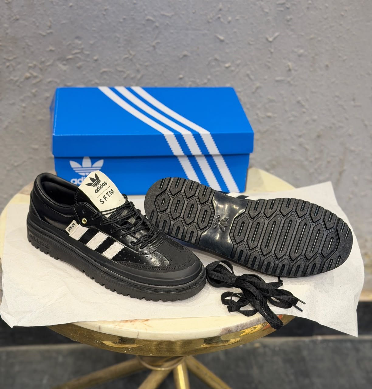 Black and white retro sneakers with contrasting side stripes, perforated panels, and chunky black soles