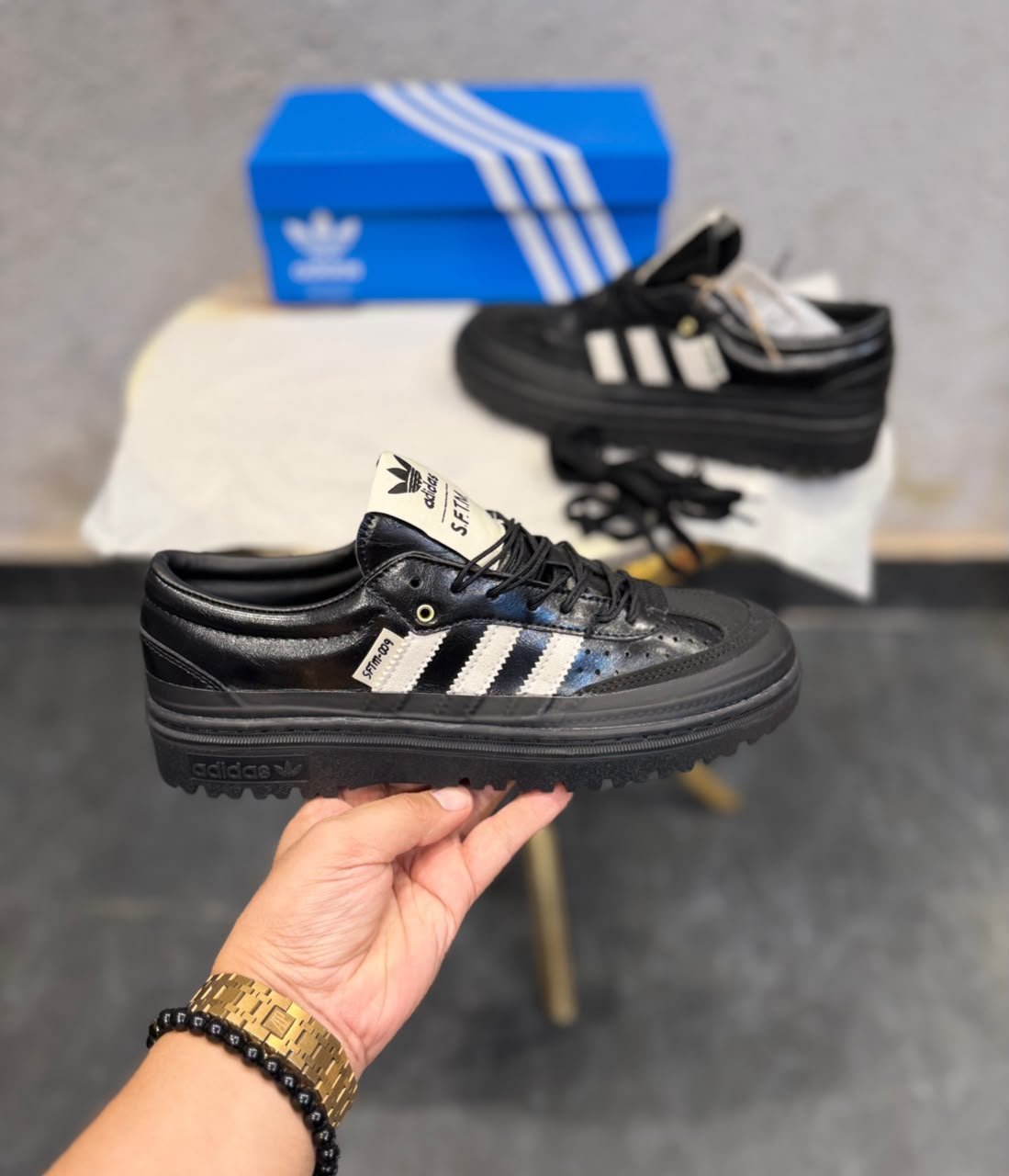 Black and white retro sneakers with contrasting side stripes, perforated panels, and chunky black soles