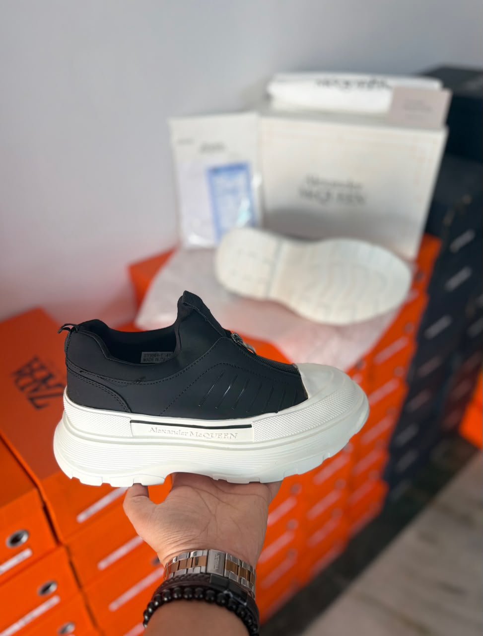 Black Zip Sneakers – Contemporary Luxury Streetwear (2) Black zip sneakers featuring a minimalist black upper, front zipper closure, and chunky white outsole with geometric tread.