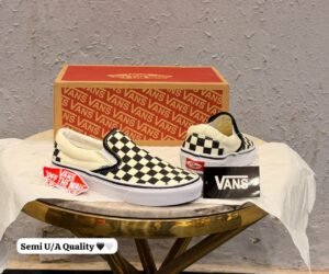 Black and cream checkerboard slip-on sneakers with a low-top silhouette and white sole