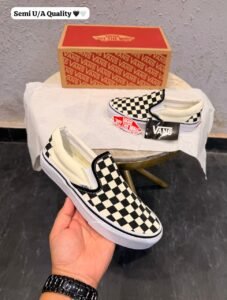 Black and cream checkerboard slip-on sneakers with a low-top silhouette and white sole