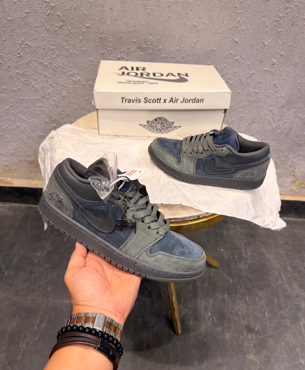 Blue and grey low-top sneakers with layered panels, perforated toe detailing, dark outsole, and decorative keychain
