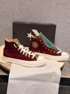 Burgundy high-top canvas sneakers with teal multicolour plaid accents, gold-tone eyelets, decorative side patches, and white rubber soles