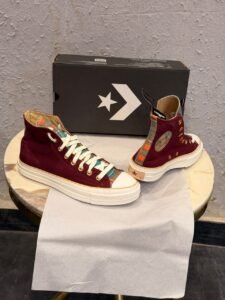 Burgundy high-top canvas sneakers with teal multicolour plaid accents, gold-tone eyelets, decorative side patches, and white rubber soles