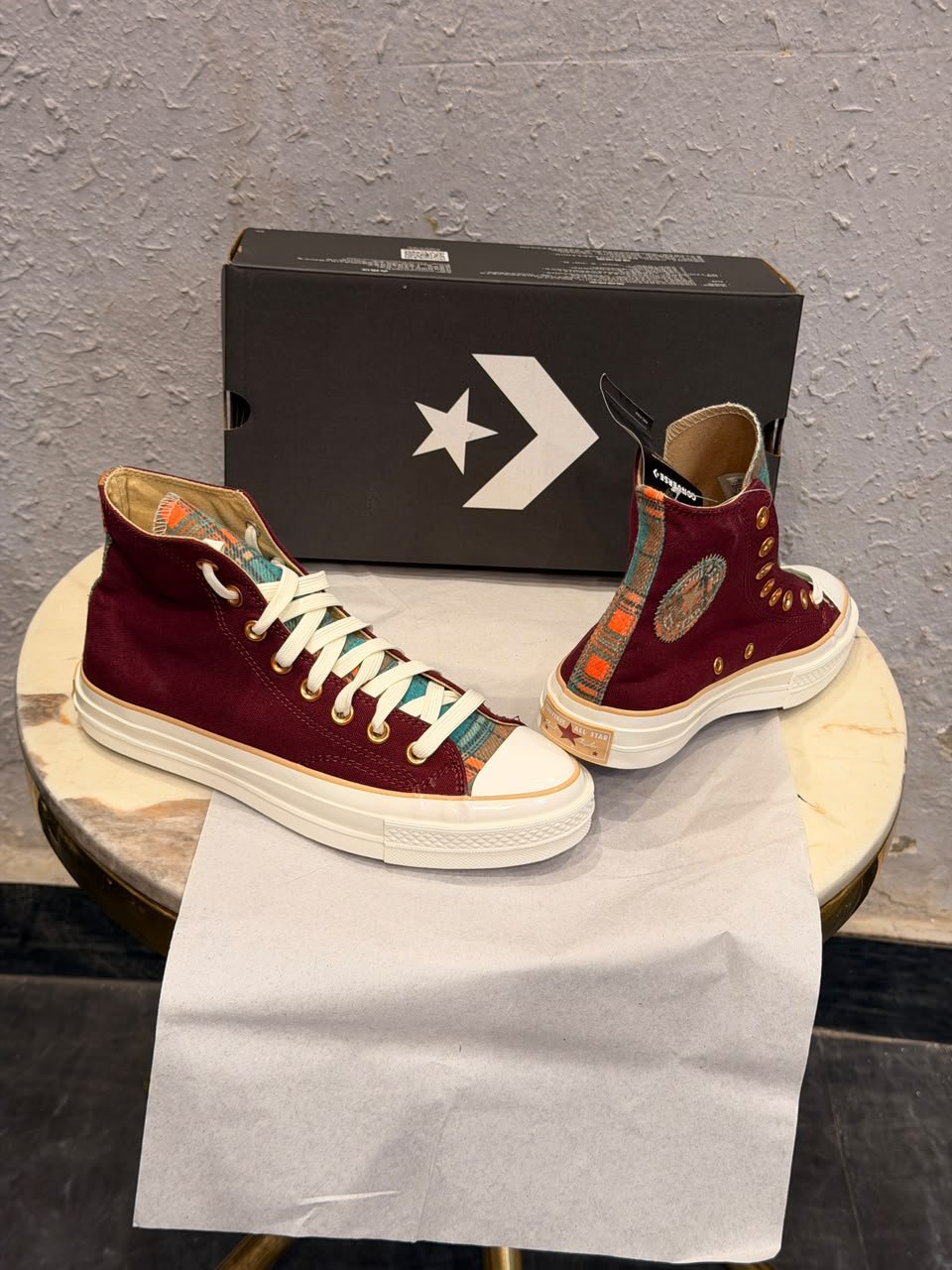 Burgundy high-top canvas sneakers with teal multicolour plaid accents, gold-tone eyelets, decorative side patches, and white rubber soles
