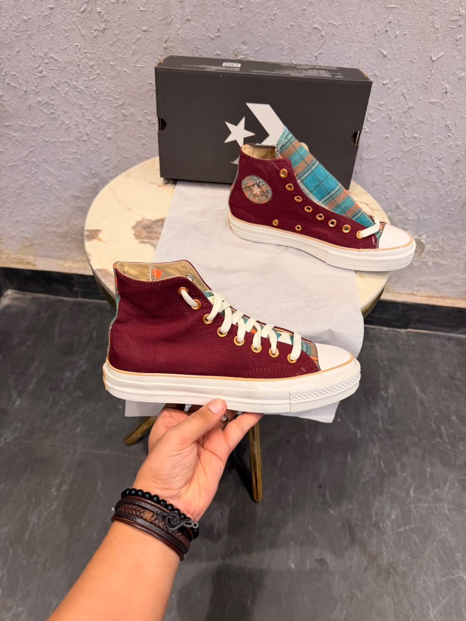Burgundy high-top canvas sneakers with teal multicolour plaid accents, gold-tone eyelets, decorative side patches, and white rubber soles