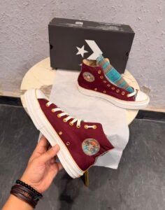 Burgundy high-top canvas sneakers with teal multicolour plaid accents, gold-tone eyelets, decorative side patches, and white rubber soles
