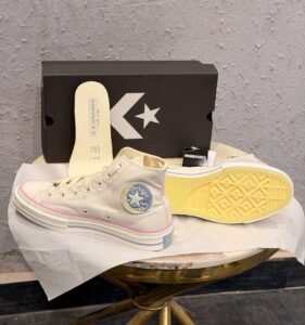 Celestial white high-top sneakers with pink trim, blue ankle emblem, and yellow outsole