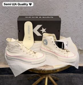 Celestial white high-top sneakers with pink trim, blue ankle emblem, and yellow outsole