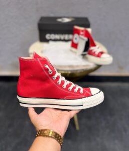 Red mid-top sneakers with cream laces, a rubber toe cap, and an off-white striped sole