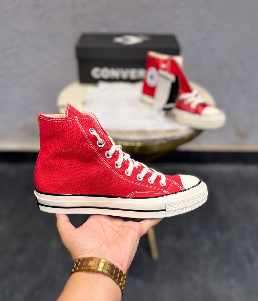 Red mid-top sneakers with cream laces, a rubber toe cap, and an off-white striped sole