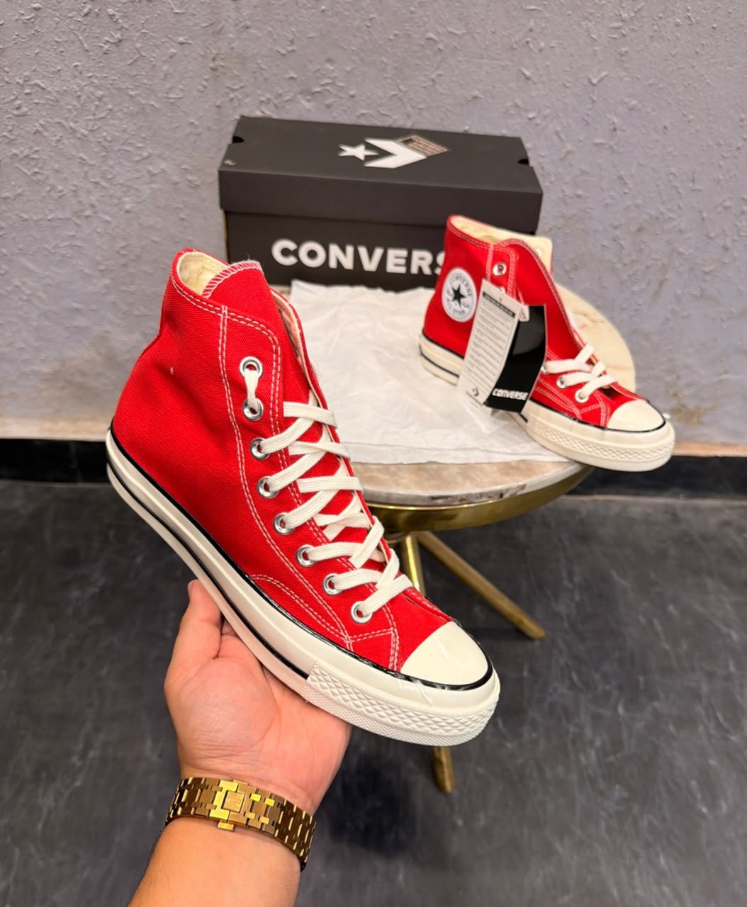 Red mid-top sneakers with cream laces, a rubber toe cap, and an off-white striped sole