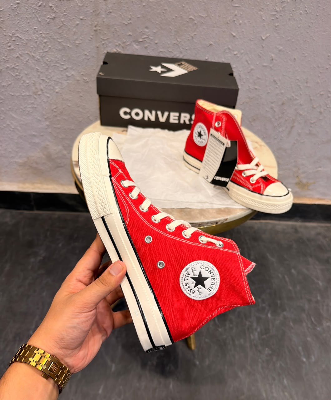 Red mid-top sneakers with cream laces, a rubber toe cap, and an off-white striped sole