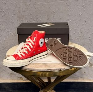 Red mid-top sneakers with cream laces, a rubber toe cap, and an off-white striped sole