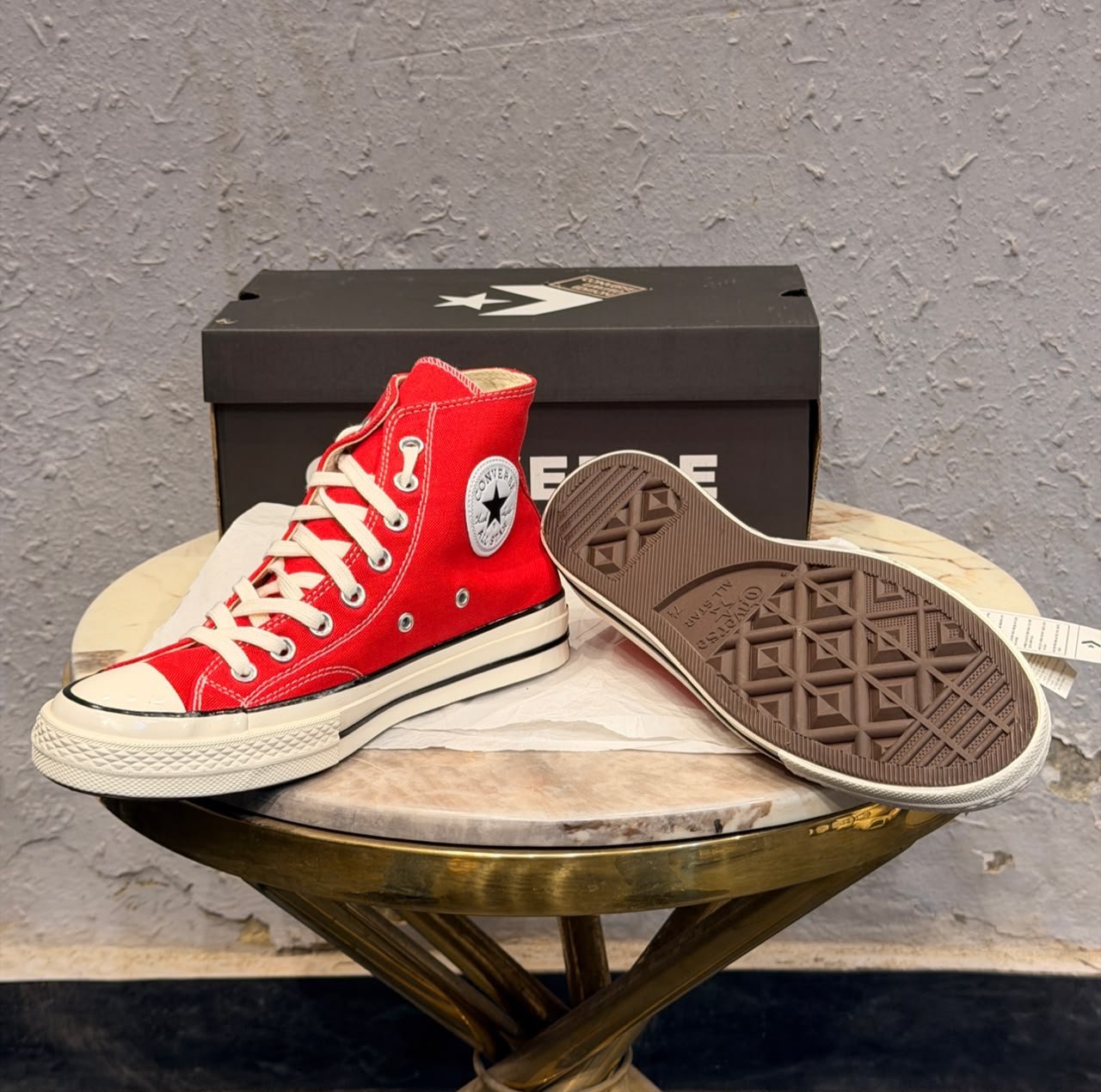 Red mid-top sneakers with cream laces, a rubber toe cap, and an off-white striped sole