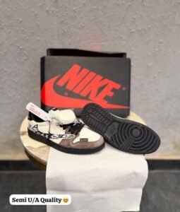 Cream and brown low top sneakers with layered overlays, black laces, patterned side detailing, and a black textured outsole