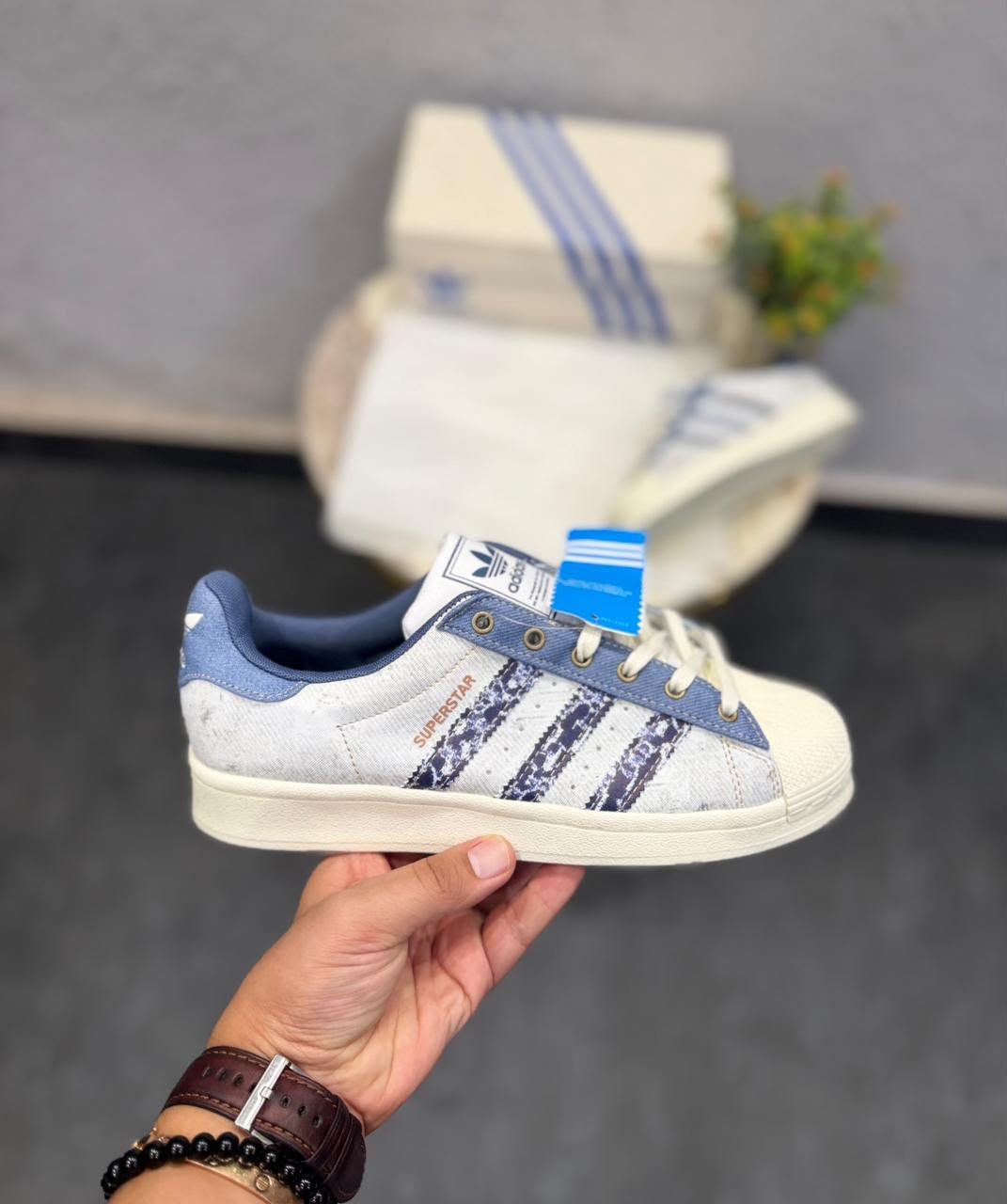 White and blue denim-style low-top sneakers featuring patterned side stripes, cream laces, and a textured shell-style toe.