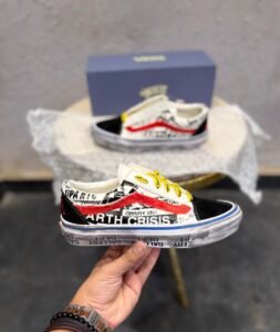 Graphic-print low-top sneakers with white panels, black toe detailing, red accents, yellow laces, and a brown gum-style outsole