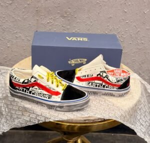 Graphic-print low-top sneakers with white panels, black toe detailing, red accents, yellow laces, and a brown gum-style outsole