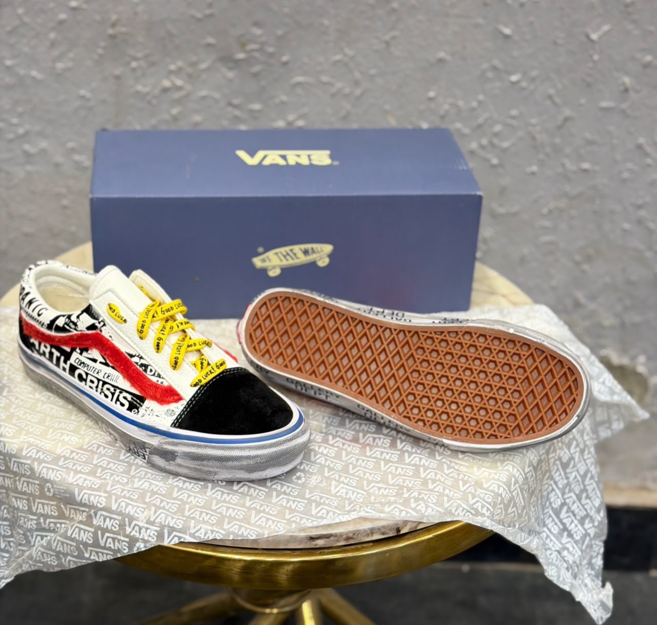 Graphic-print low-top sneakers with white panels, black toe detailing, red accents, yellow laces, and a brown gum-style outsole
