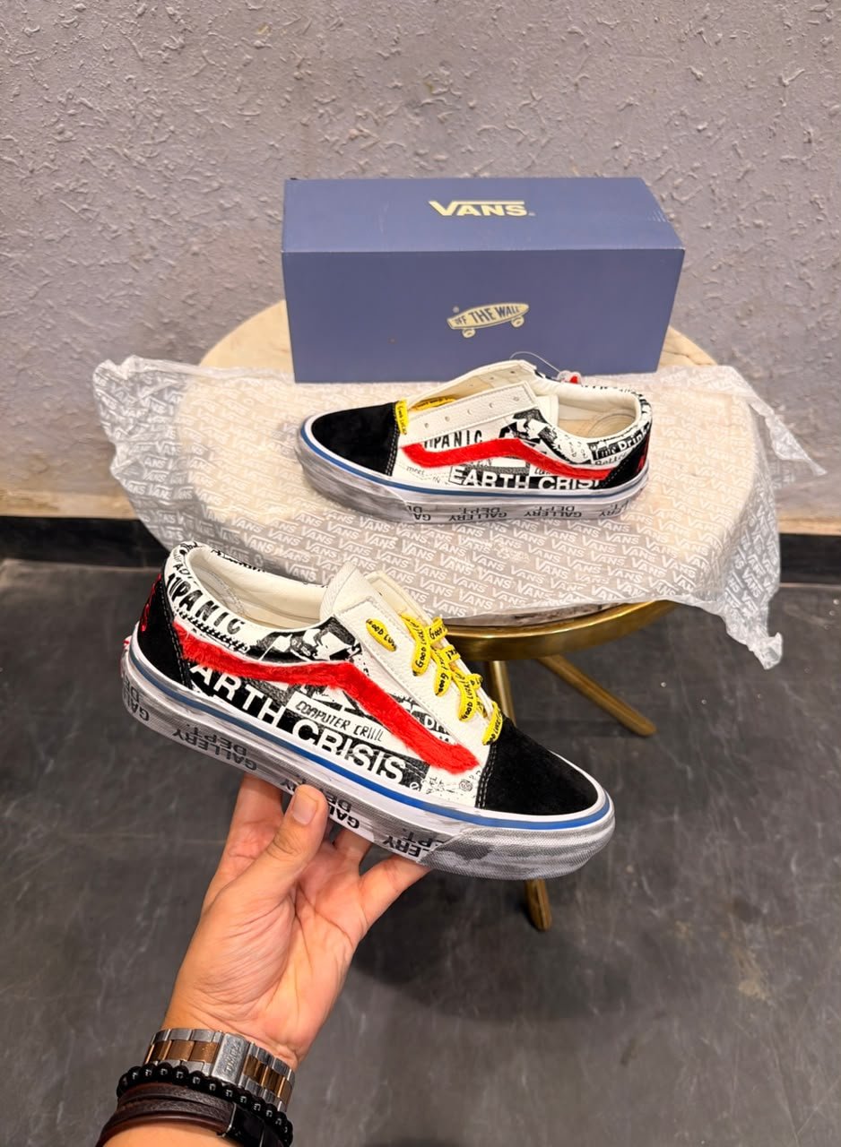 Graphic-print low-top sneakers with white panels, black toe detailing, red accents, yellow laces, and a brown gum-style outsole