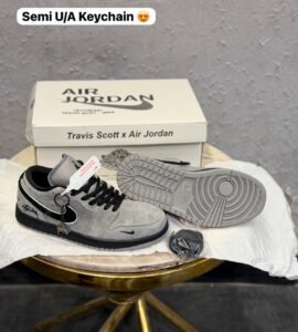 Grey and black low-top sneakers with contrasting panels, textured outsole, and decorative keychain