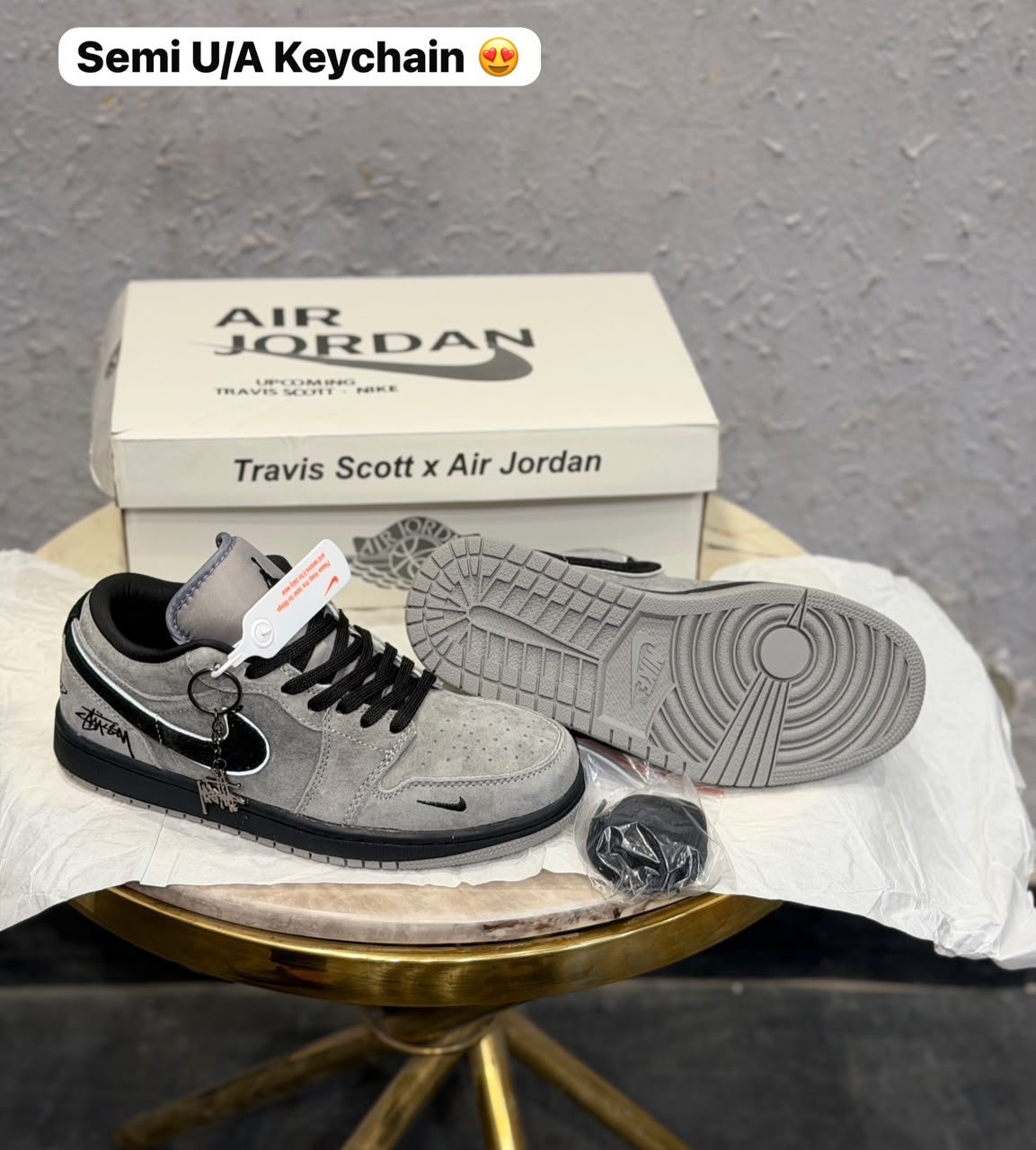 Grey and black low-top sneakers with contrasting panels, textured outsole, and decorative keychain