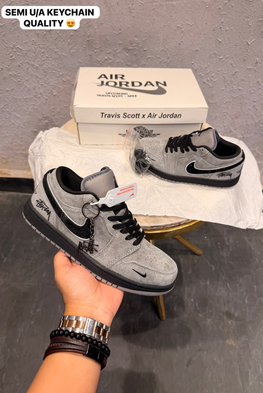 Grey and black low-top sneakers with contrasting panels, textured outsole, and decorative keychain