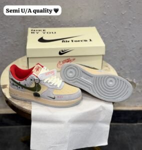Grey low-top sneakers with olive-green accents, red lining, cream toe panels, decorative star graphics, and a grey circular-patterned outsole