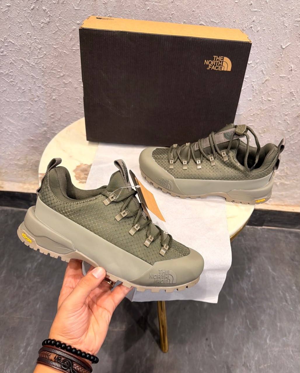 Khaki green outdoor-style sneakers with a grid-textured upper, reinforced-looking toe panel, and chunky taupe tread outsole