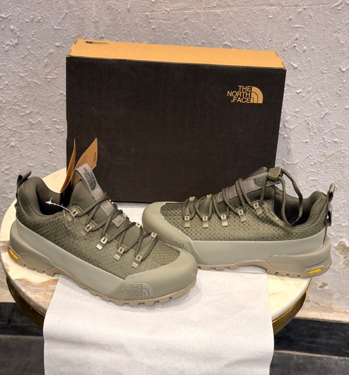 Khaki green outdoor-style sneakers with a grid-textured upper, reinforced-looking toe panel, and chunky taupe tread outsole