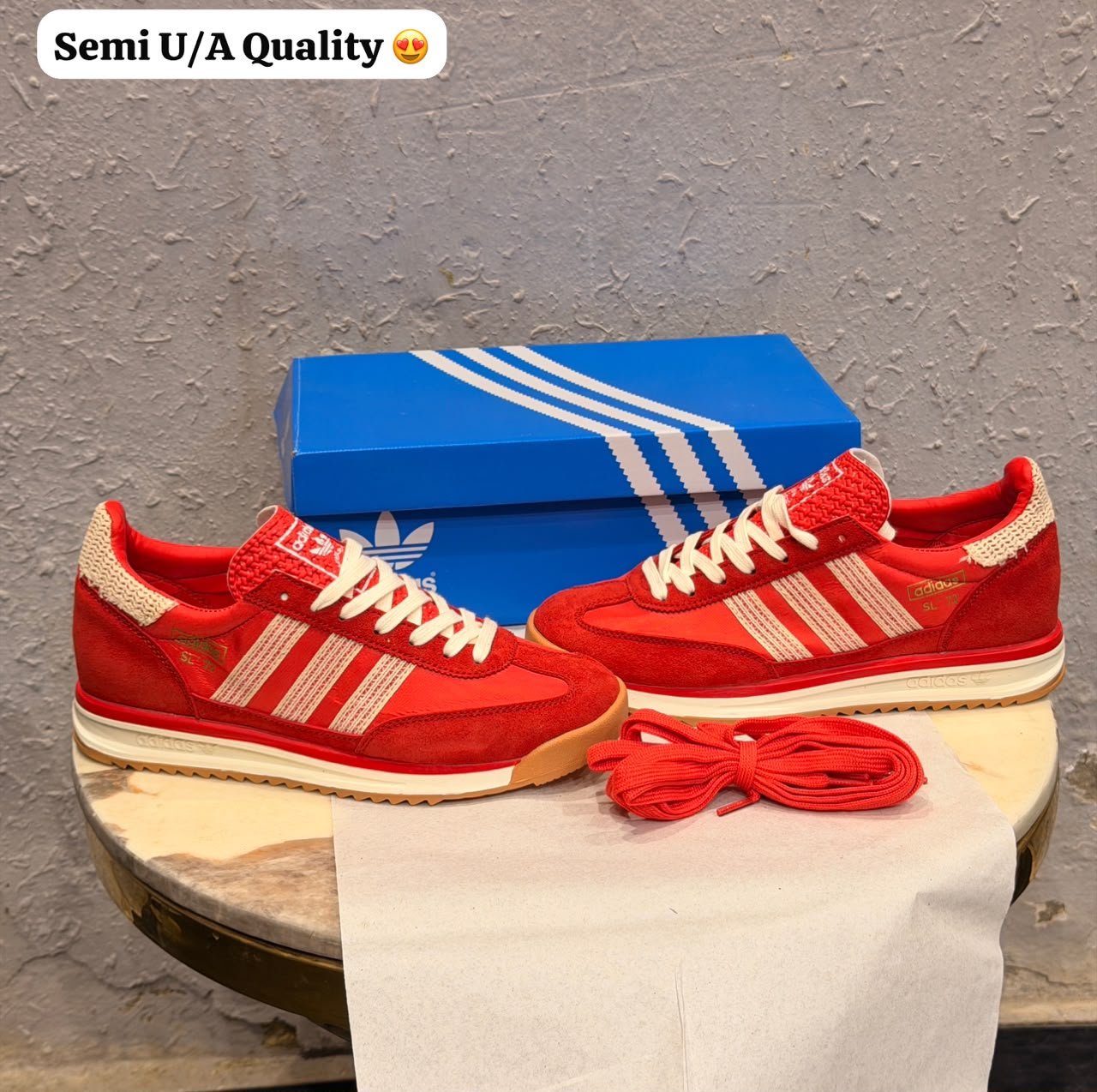 Red low-top retro sneakers with cream-coloured stripes, cream laces, gum-brown outsoles, and an additional pair of red laces